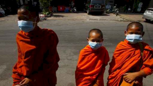 Biksu Buddha yang memakai masker wajah sambil menerima sedekah dari umat di Phnom Penh, Kamboja, Rabu (10/3/2021). (AP Photo/Heng Sinith)