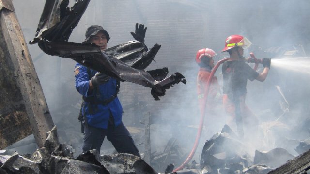 (Pemadam kebakaran di lokasi kebakaran Kelurahan Karuwisi, Makassar. Petugas sempat menemui kendala karena akses jalan sempit dan warga yang berkerumun menonton)