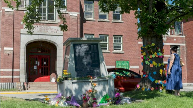 Seorang wanita membaca kartu belasungkawa yang diikat ke pohon di sebelah monumen untuk para penyintas bekas Sekolah Perumahan India Kamloops, dimana ditemukannya sisa-sisa jasda 215 anak, di Kamloops, British Columbia, Kanada. (Foto: Reuters)