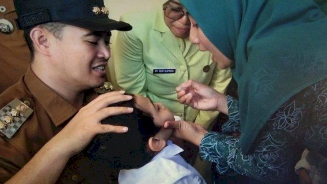 Bupati Yusran-Ketua TP PKK Nurlita saat memberikan vaksin polio ke anak.